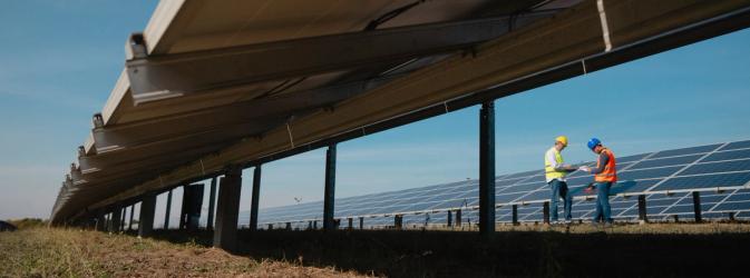 Workers on site next to rows of solar panels