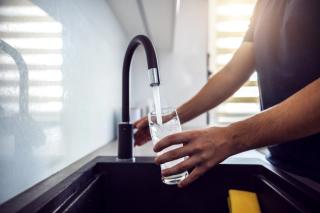 Close up of man pouring fresh water from kitchen sink